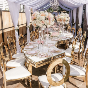 White curved table with gold geometric legs and banquet chairs