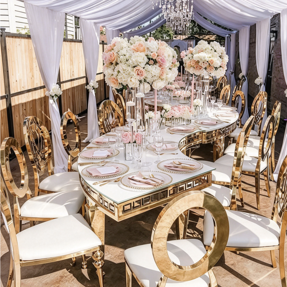 White curved table with gold geometric legs and banquet chairs