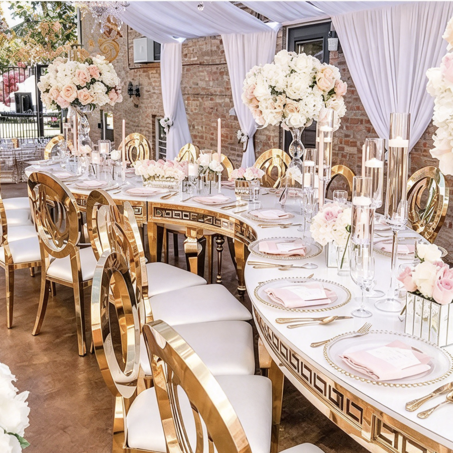 White curved table with gold geometric legs and banquet chairs